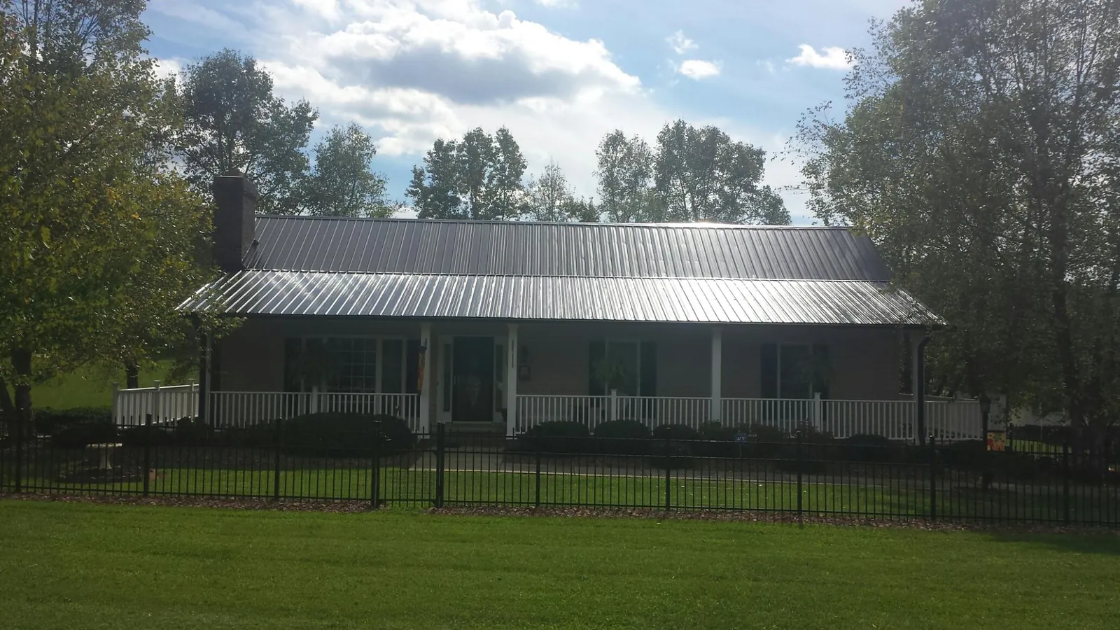 Gray metal roof on a brick ranch with a full width front porch — Gutter Guard Installation work by our crew in New Providence