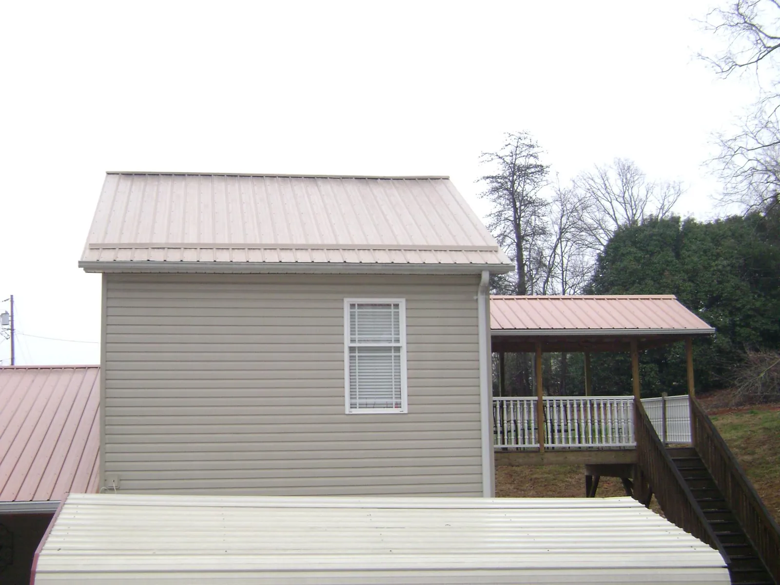 Tan metal roofs on a two story addition and attached porch, from a Roof Replacement job in New Providence
